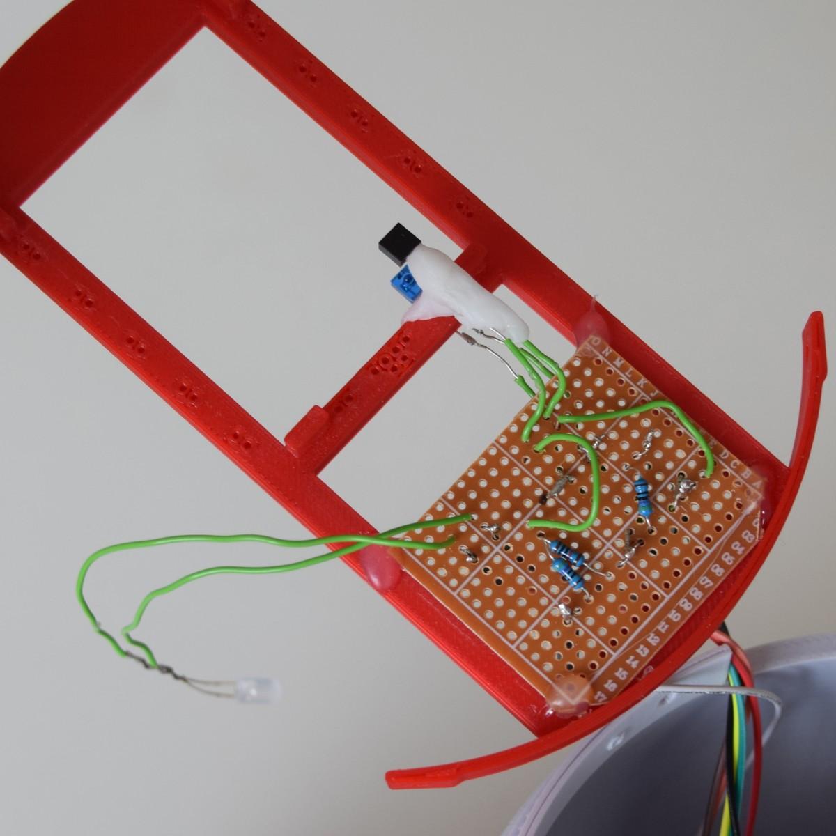 Alle Bauteile wurden auf einer Platine verlötet und auf den Rahmen geklebt. Die Lichtschranke ist zusätzlich mit Polymorph fixiert, damit man die Drähte nicht beim Einschieben der QR-Code-Karten verbiegt.